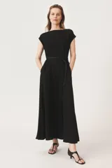 Vestido largo negro de tejido fluido, con cuello redondo, mangas cortas con dobladillo y cierre trasero con cremallera oculta.