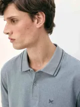 Polo de hombre color gris oscuro jaspeado, con cuello y puños de manga con ribete negro. Presenta un pequeño logo bordado en el pecho.