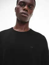 Sweater de lana merino color negro, de corte regular y cuello redondo. Presenta puños y dobladillo de punto acanalado, y el logotipo de monograma tonal de Calvin Klein bordado en el pecho.
