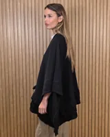 Ruana tejida de algodón en color negro, con diseño amplio y volados en el borde inferior.