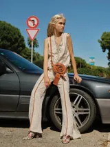 Pantalón de brocato color crudo con diseño floral en relieve, de tiro medio, corte acampanado con tajos laterales y cuatro bolsillos.