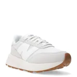 Championes urbanos New Balance modelo 370, de diseño retro inspirado en los años 70. Presentan una combinación de tonos blancos y gris claro, con paneles de malla y superposiciones de gamuza. Incluyen el logo N en los laterales, cierre con cordones y una suela de goma con plataforma y base color caramelo.