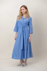 Vestido midi cruzado de seda con estampado de rayas celestes y blancas, escote en V con solapa, mangas tres cuartos y detalle de nudo drapeado en la cintura.