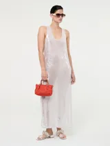 Vestido largo de corte recto con escote redondo y tirantes anchos, completamente cubierto de lentejuelas brillantes. Presenta tajos laterales en el ruedo.