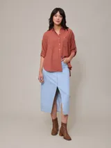 Camisa color beige de algodón y lino, con cuello clásico, cierre frontal con botones, mangas largas con puños abotonados, dos bolsillos con solapa en el pecho y corte holgado.