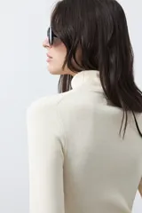 Polera de manga larga y cuello alto, confeccionada en tejido de punto fino, con un ajuste ceñido al cuerpo.