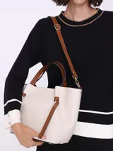 Bolso tipo tote color blanco hueso, con textura granulada y detalles en cuero marrón.