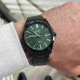 Reloj CASIO con caja y correa de acero inoxidable color negro, esfera verde con diseño cuadriculado, agujas y marcadores dorados, indicador de fecha y cristal mineral.