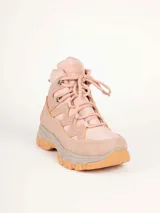 Bota de trekking color rosado con cordones al tono, cuello acolchado, ganchos metálicos para los cordones y suela dentada con plataforma gris y caramelo.