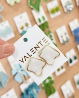 Aros tipo caravanas de diseño geométrico con centro esmaltado en color blanco y borde metálico dorado.