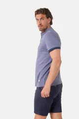 Remera blanca de manga corta con cuello mao y cierre frontal parcial con botones. Presenta detalles en color gris azulado en el cuello y en los bordes de las mangas.