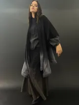 Ruana larga de lana merino color gris con cuello plisado de fieltro. Diseño degradado con terminación en flecos.