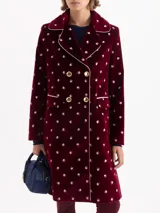 Tapado de velvet color bordó con estampado floral en blanco, forrado en jacquard beige. Presenta cuello tipo Peter Pan con solapa redondeada y vivo en contraste que enmarca cuello, cartera y bolsillos. El acceso es mediante cruce diagonal con cuatro broches dorados. Lleva recortes en cintura, costadillos y pinzas que estructuran la silueta, junto con hombreras que aportan porte. Largo por debajo de la rodilla.