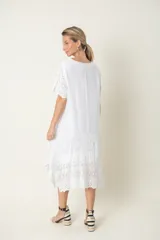 Vestido blanco de seda con mangas cortas y bajo con detalles de broderie.