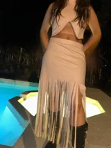 Pollera midi color nude, de corte recto y tiro alto, con flecos largos en el ruedo y tajo lateral.