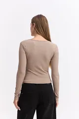 Remera de manga larga color beige, con ajuste al cuerpo y costuras decorativas visibles en el frente que realzan la silueta.