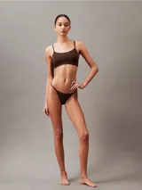 Bombacha tipo colaless Calvin Klein de la línea Ideal Cotton, confeccionada en mezcla de algodón y elastano. Presenta un diseño de talle medio con laterales y parte trasera estilo cuerda, y cuenta con una cinturilla elástica con el logo de la marca.