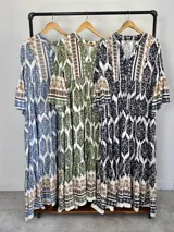 Maxi vestido largo de fibrana en color blanco con estampado paisley y geométrico en tonos azules y tostados, con escote en V, mangas largas amplias y diseño holgado con volados en la falda.