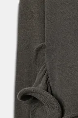 Jersey de punto gris oscuro con cuello redondo y manga larga, con bajo asimétrico acabado en volante con varilla metálica interior.