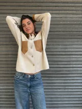 Camisa de tejido fino en lana color beige, con detalles en cuero color suela en cuello, bolsillos frontales y puños. Presenta cierre frontal con botones.