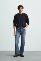 Jersey color crudo de tejido de punto, con cuello redondo y mangas largas. Corte amplio y terminaciones en rib.