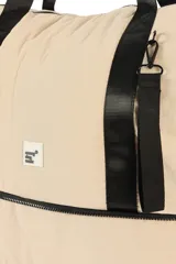 Bolso de nylon color beige, tipo shopper, con asas de mano y tiras negras. Cuenta con compartimento inferior con cierre y un llavero colgante desmontable.