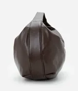 Cartera modelo hobo de gran tamaño, confeccionada en poliuretano con acabado brillante y textura suave. Presenta un diseño de media luna con asa ancha integrada para llevar al hombro y cierre superior.