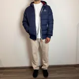 Campera tipo puffer color bordó con capucha, cierre frontal blanco y puños de tejido elástico. Presenta el logo de la marca bordado en el pecho.