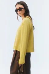 Sweater de tejido de punto verde, con calce regular levemente suelto, escote redondo y mangas largas con puños acanalados.