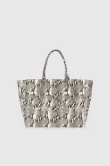 Bolso tipo tote de lona con estampado de piel de serpiente en tonos grises y blancos. Presenta doble asa superior y el logo de la marca Anine Bing estampado en el frente.