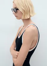 Vestido midi de punto fino en color negro, con diseño recto y cuello redondo. Presenta tirantes anchos con detalle de ribete en contraste en tonos blanco y tostado.