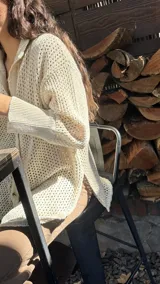 Camisa tejida en punto calado color marrón con hilo de algodón y lurex. Silueta oversize, mangas 3/4 ligeramente abullonadas, cuello camisero clásico y botonadura frontal con botones metálicos dorados.