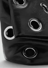 Bolso tipo tote de color negro, confeccionado en poliuretano, con diseño de ojales metálicos plateados distribuidos por toda la superficie y asas largas para llevar al hombro.