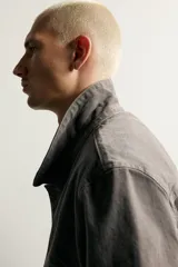Cazadora de denim de algodón en color gris oscuro con efecto lavado, corte relaxed fit, cuello camisero, bolsillos delanteros con solapa en el pecho y cierre frontal con botones.