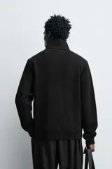 Chaqueta regular fit de cuello subido, confeccionada en tejido técnico interlock de algodón con elasticidad. Presenta cierre frontal con cremallera, manga larga con puños en rib y bolsillos de vivo en la cadera.