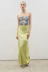 Vestido largo con diseño bicolor, cuerpo superior estampado con aberturas y hebillas metálicas, y falda inferior de satén en color verde lima. Presenta escote halter con cordones para anudar al cuello.