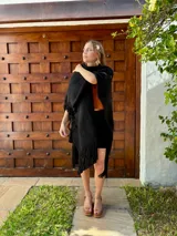 Ruana tejida en lana, de color negro, con diseño de flecos en los bordes inferiores.