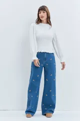 Jean de corte wide leg en color azul medio, con diseño de pequeños bordados dispersos en toda la prenda. Presenta cierre frontal con botón y bolsillos laterales.