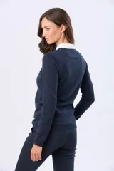 Buzo tejido en hilo de algodón color beige, con cuello redondo y manga larga. Presenta un corte clásico y un pequeño detalle metálico en la parte inferior izquierda.