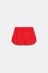 Shorts de tiro bajo color amarillo claro, confeccionado en tejido con lino. Presenta cintura elástica ajustable con cordones y aberturas laterales en el bajo.