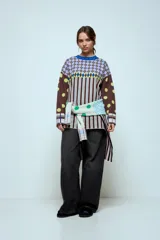 Sweater de punto con diseño geométrico y a rayas, de corte holgado y manga larga. Presenta un patrón combinado de lunares en las mangas, rombos en la parte superior y rayas verticales en el cuerpo.