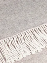 Bufanda de estilo clásico en color beige, confeccionada en tejido suave y cálido, con detalle de flecos en los extremos.