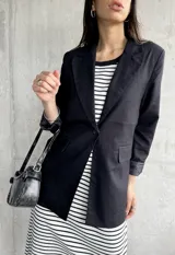 Blazer negro de lino con solapas de muesca, cierre con un botón y bolsillos delanteros.