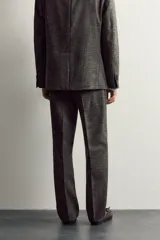Pantalón de traje regular fit de la colección especial Aaron Levine x Zara, confeccionado en mezcla de lana y lino de color gris. Presenta diseño con pinzas delanteras, bolsillos laterales y traseros de doble vivo con botón, y cierre frontal con cremallera y gancho metálico oculto.
