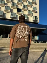 Remera marrón con estampado blanco con la palabra "Brooklyn" en el frente.