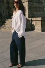 Pantalón barrel color azul marino, de tiro bajo, pernera holgada con diseño redondeado que se estrecha hacia el tobillo, con bolsillos delanteros y cierre frontal.