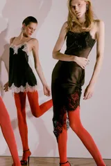 Top negro de tejido satinado con escote pico y tirantes finos. Presenta aplicación de encaje color crema en el escote y en el bajo, con un acabado en línea evasé.