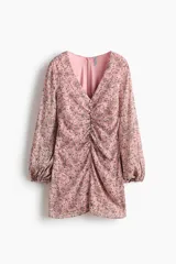 Vestido corto de gasa arrugada en color rosado con estampado floreado, escote en V y costura fruncida central con botones decorativos forrados. Cuenta con mangas globo largas con puños elásticos y cierre oculto en la espalda.