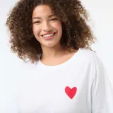 Remera blanca de corte oversize y manga corta, con estampado en la espalda que presenta corazones rojos y la palabra LOVE en letras negras.