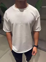 Remera de algodón pesado color blanco, con corte oversize, cuello redondo y mangas con terminación sin costura. Presenta un pequeño bordado central en el pecho.